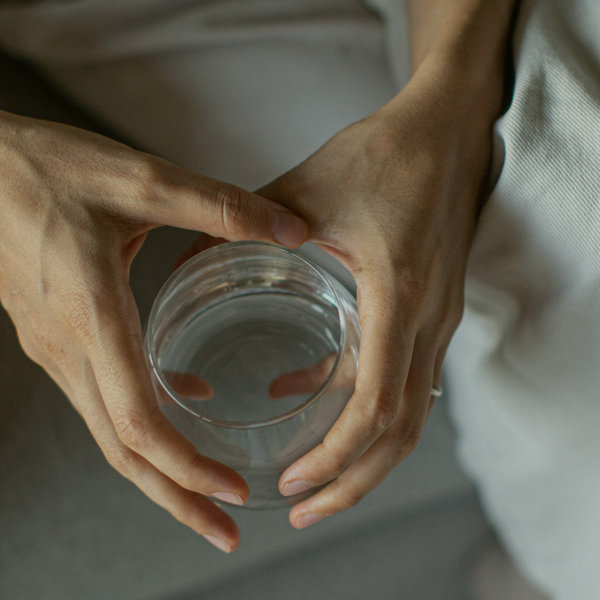 A pair of hands holding a glass of water
