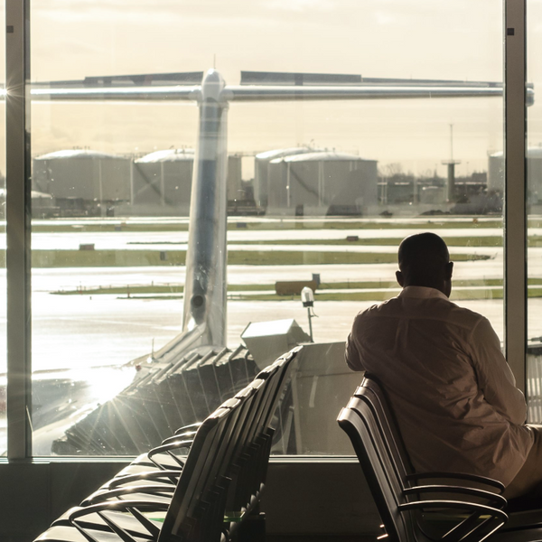 A man sitting an an airport gate with the plane and airport tarmac in view out of the window