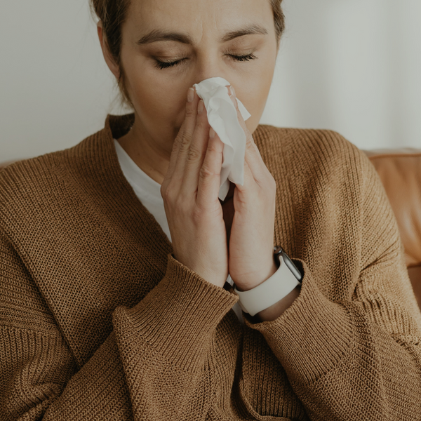 A woman blowing her nose in to a tissue
